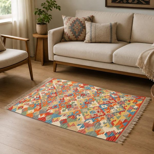Bunter Kelim Teppich auf Holzboden vor einem hellen Sofa im Wohnzimmer