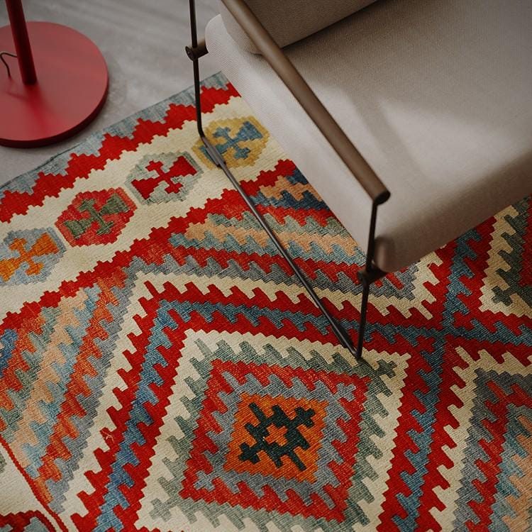 Großer roter Kelim mit Rauten unter einem Sessel im Wohnzimmer