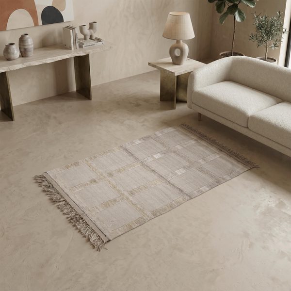 Naturfarbener Gabbeh Kelim Teppich vor einem hellen Sofa in einem Wohnzimmer mit Konsole und Lampe