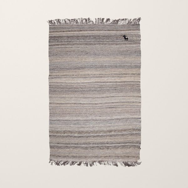 Kelim in Grau und Beige von oben auf cremefarbenem Hintergrund mit kleiner Ziege